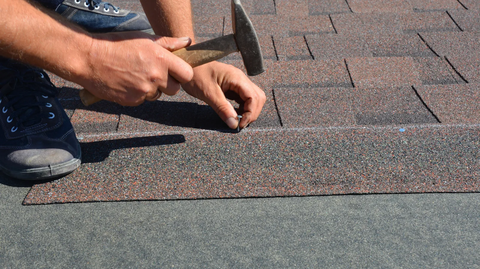 Nail hammered into an asphalt shingle by a roofer